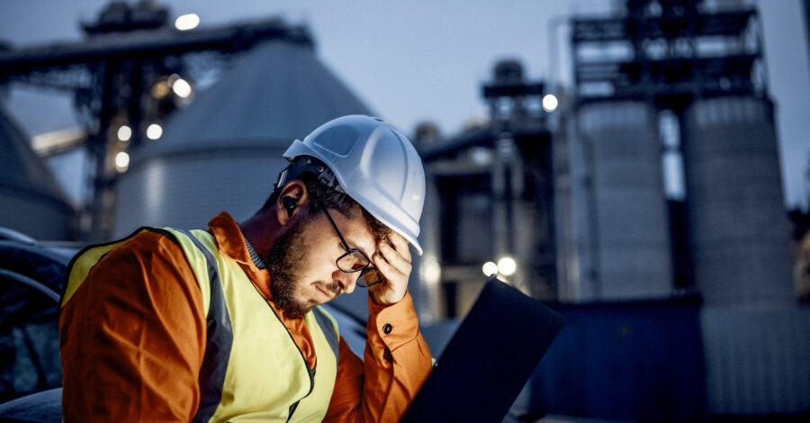 Young engineer having a problem during his night shift in oil rafinery. A shot of a young engineer holding his had bcause having a big problem during his night shift in the oil rafinery.