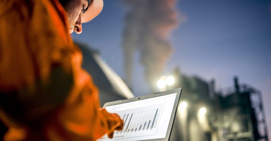 Engineer with laptop working in oil refinery Engineer man with portable computer working late nightshift in petroleum factory.
