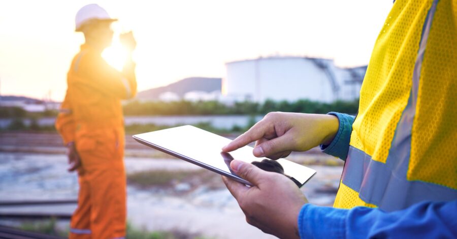 Engineer wearing safety helmet using tablet with oil refinery. Engineer wearing safety helmet using tablet with oil refinery industry plant background.
